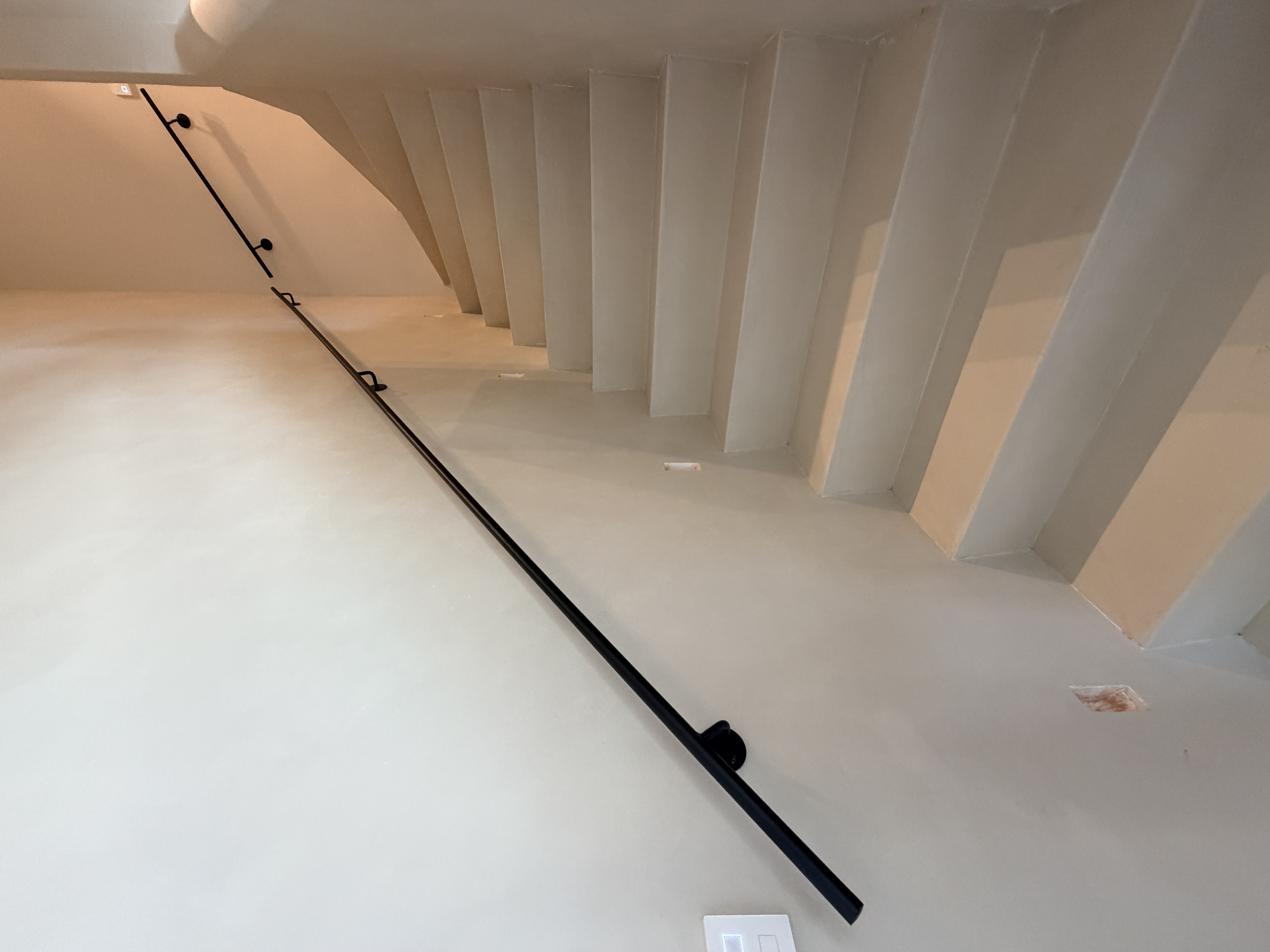 S-Gravenzande stalen trapleuning: overzicht van de moderne opgang, met de elegante zwarte leuning als blikvanger langs de lichte wand en houten trap