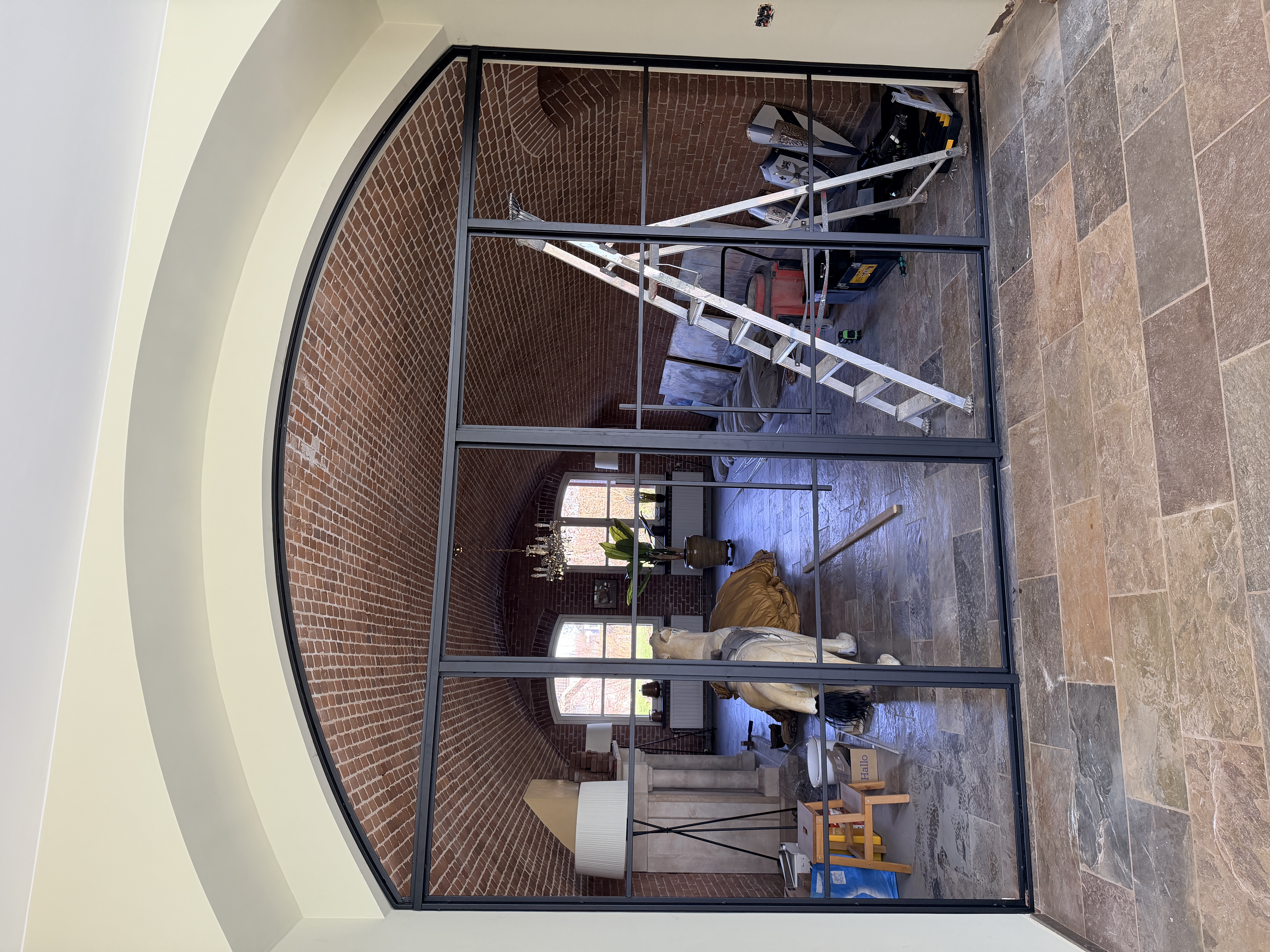 Detail van een stalen dubbele toogdeur in Werkendam, met focus op de gebogen bovenzijde en de bakstenen muur erachter