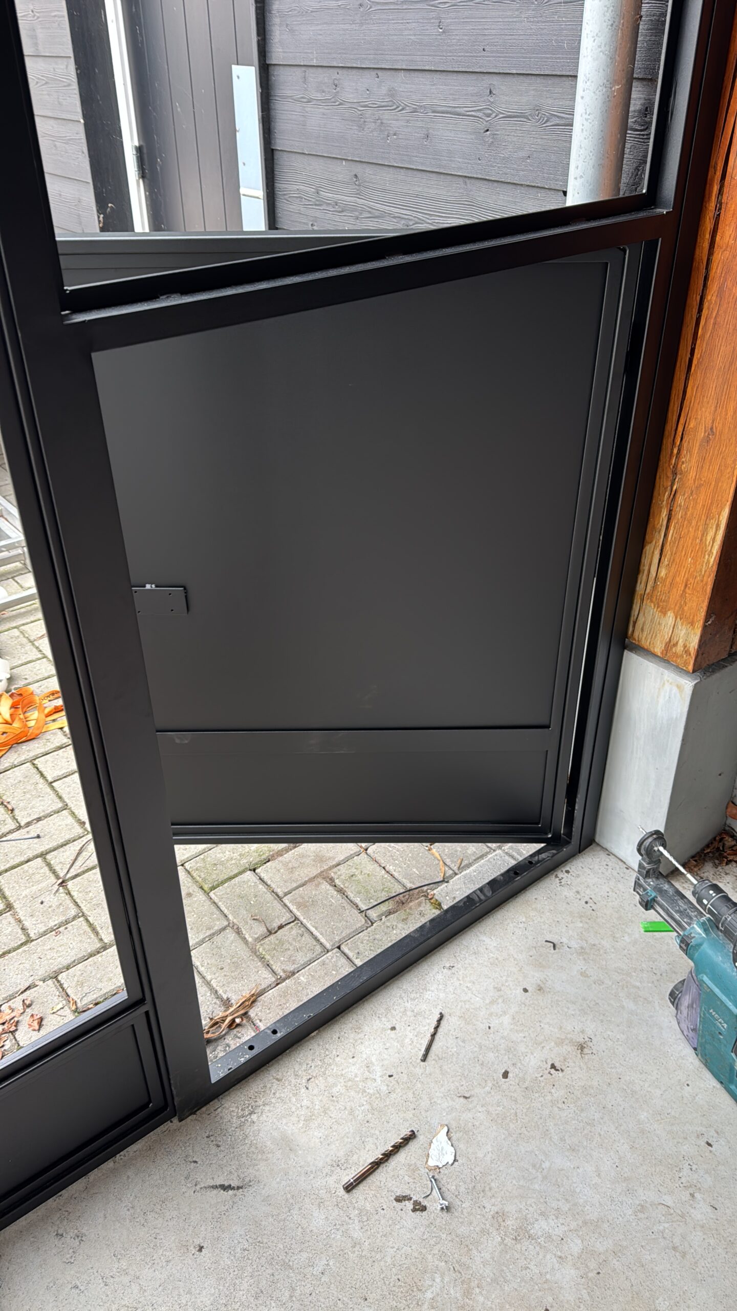 Detail van een stalen pui met geïntegreerd hondenluik in een moderne woning